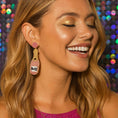 Load image into Gallery viewer, A smiling woman wearing rose wine bottle beaded earrings My Doris, featuring pink and silver beads against a colorful background.