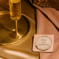 Load image into Gallery viewer, Press for champagne drink coaster beside a champagne flute on an elegant table setting.