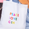 Load image into Gallery viewer, Gin tote bag featuring colorful text saying 'PEACE LOVE GIN' on a white background, perfect for gin lovers.