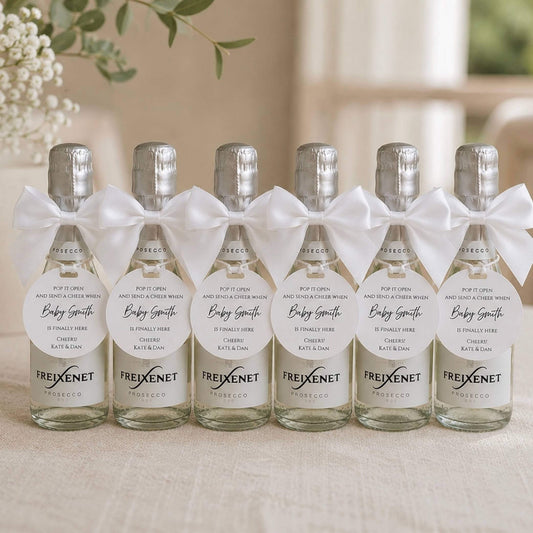 Baby shower pop the fizz bottle favour tags on mini bottles of prosecco with white bows.