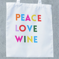 Load image into Gallery viewer, White tote bag featuring colorful text: PEACE LOVE WINE, perfect for wine lovers and trips to the winery.
