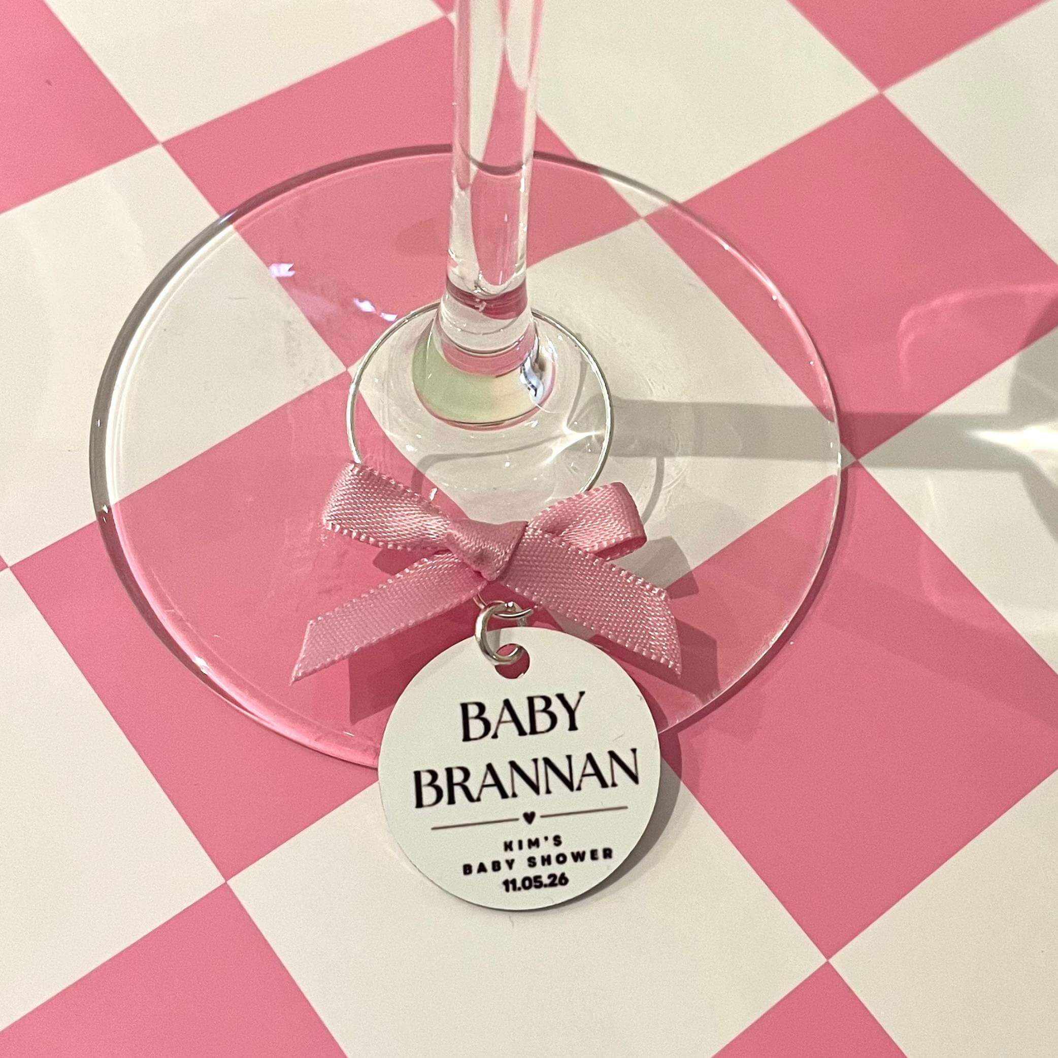 Wine glass with a 'Baby Brannan' tag on a pink and white checkered background