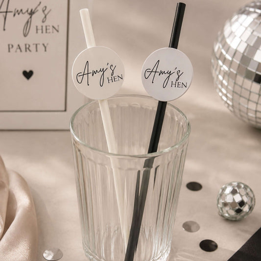 Hen party paper straws personalised toppers in a glass, featuring white and black straws with custom toppers.