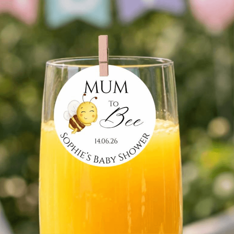 Mum To Bee edible drink topper on a champagne glass at a baby shower celebration.