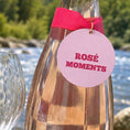 Load image into Gallery viewer, Rose Moments Bottle Charm Gift Tag on a wine bottle by the river with a pink ribbon.
