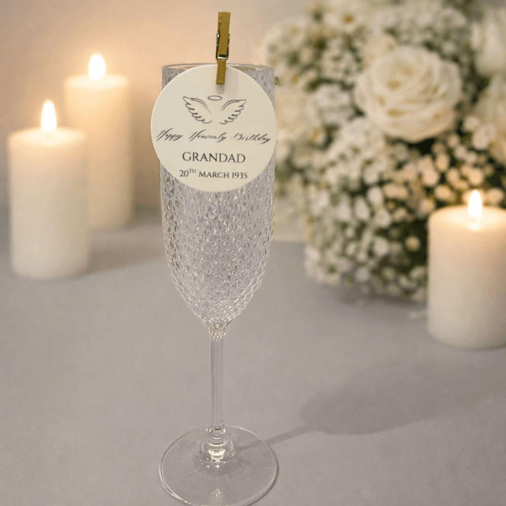 Happy Heavenly Birthday Edible Wafer Drink Toppers with a memorial tag on a flute glass surrounded by candles.