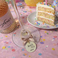 Load image into Gallery viewer, Personalised Birthday Party Wine Charms on a wine glass at a festive celebration with cake.
