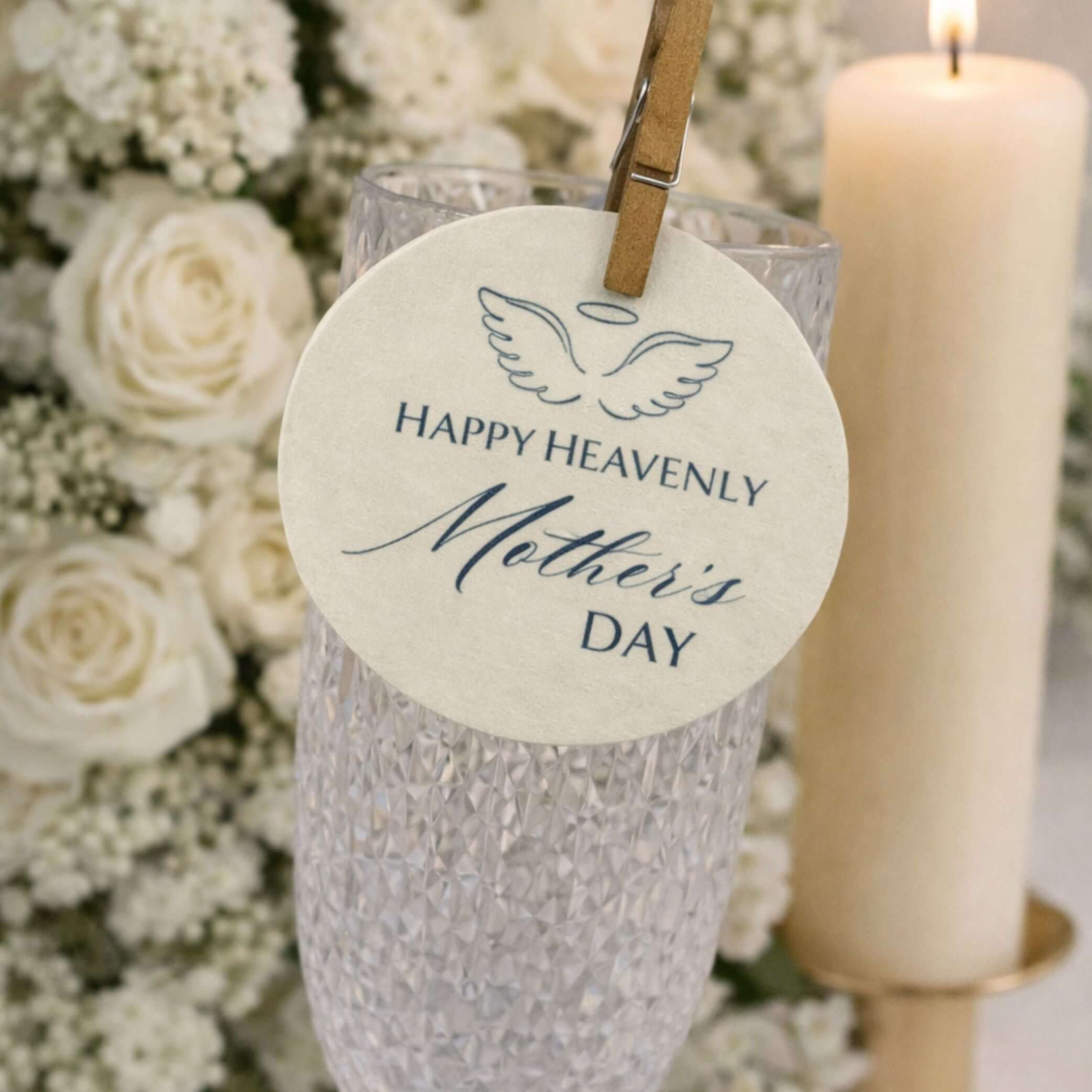 Happy Heavenly Mothers Day Edible Wafer Drink Toppers attached to a glass with flowers and candle in the background.