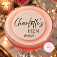 Load image into Gallery viewer, A close-up of a pink frothy cocktail in a coupe glass with a gold rim, topped with a white foam circle printed with the personalized text 'Charlotte's HEN 26.10.
