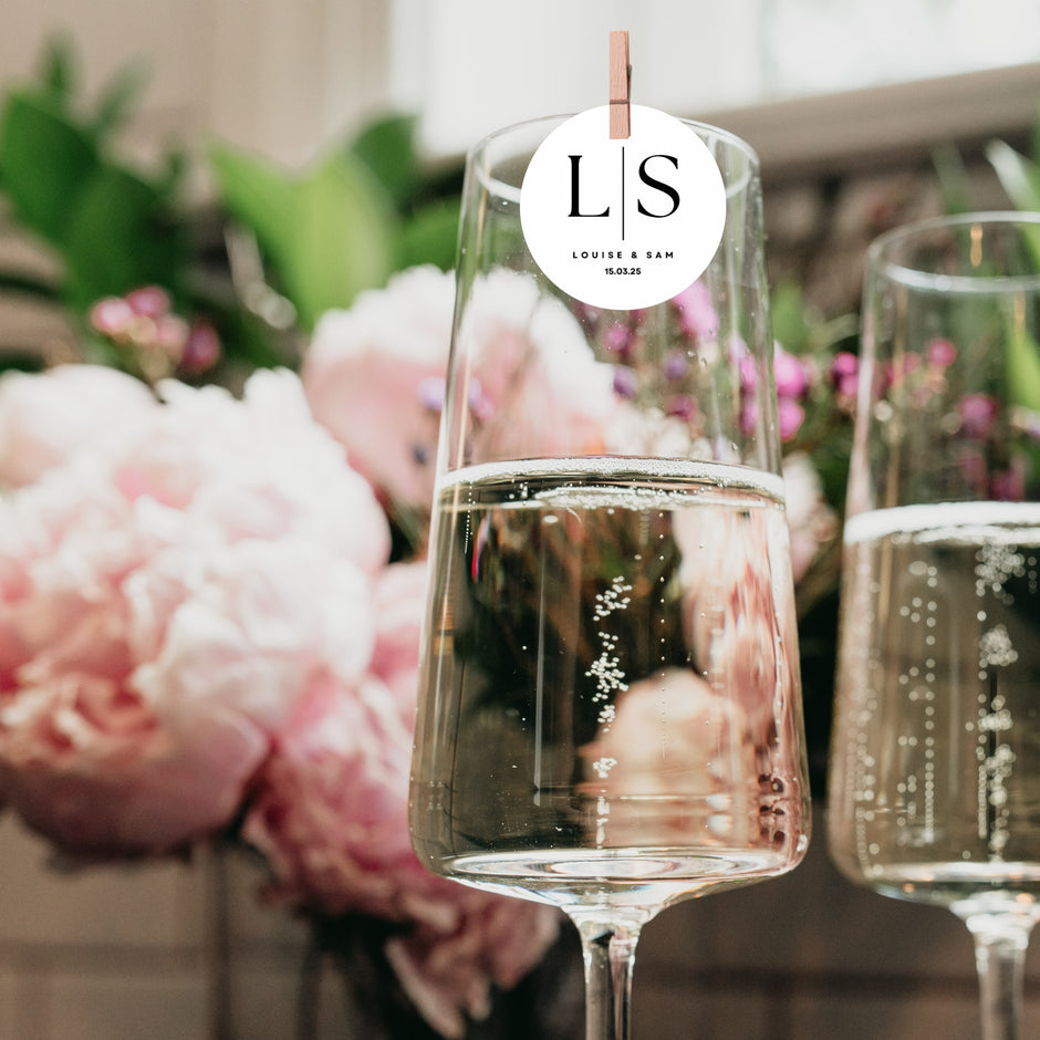 Personalised Monogram Initial Edible Cocktail Toppers in glasses with flowers, enhancing celebratory drinks.