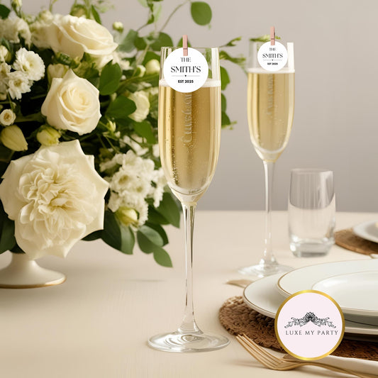 Personalised Family Name Edible Cocktail Toppers on champagne flutes with flowers in the background for wedding celebration.